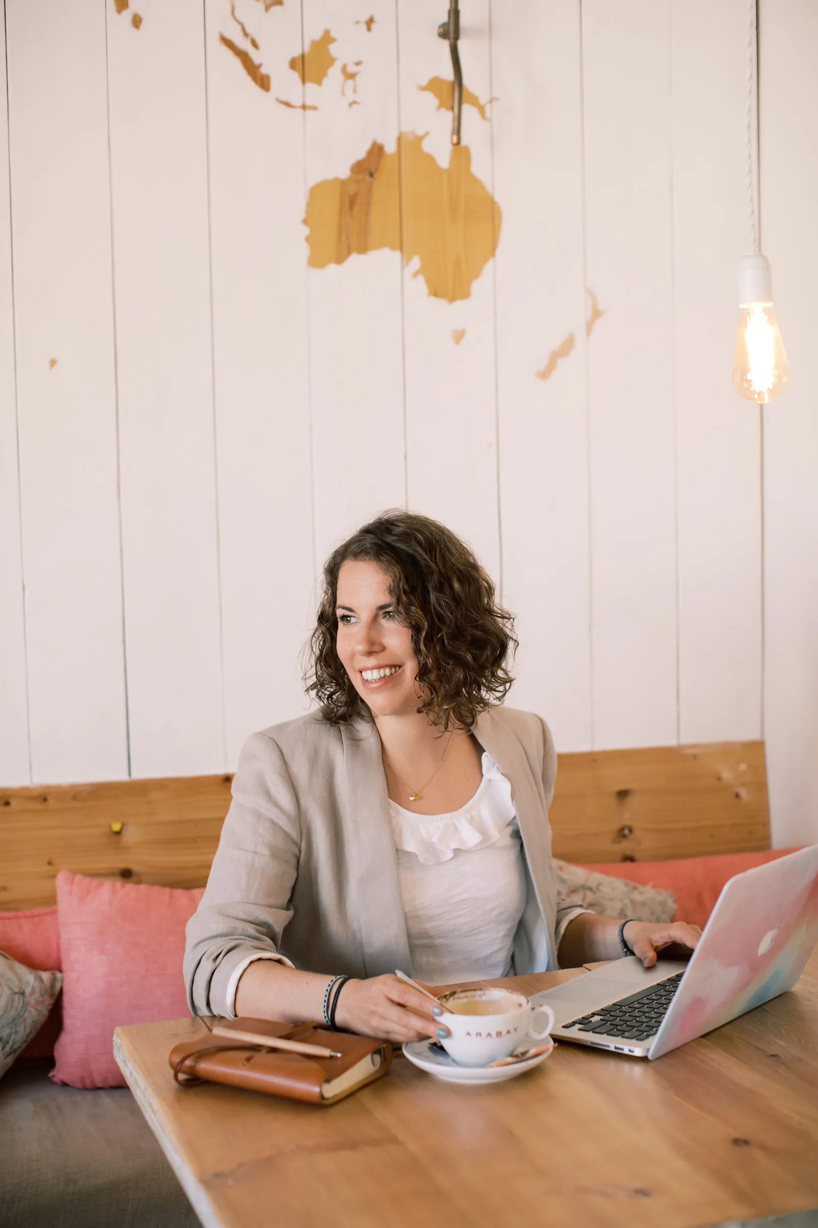 Maria smiling at a cafe table with her laptop