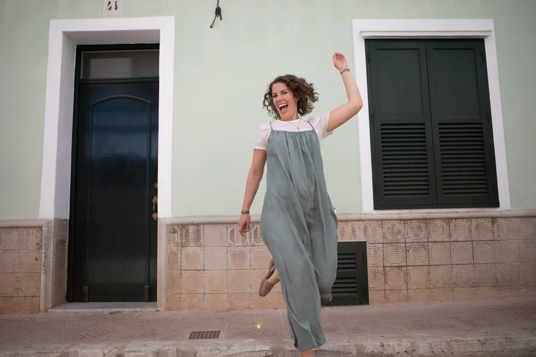 Maria jumping for joy outside a Mediterranean doorway
