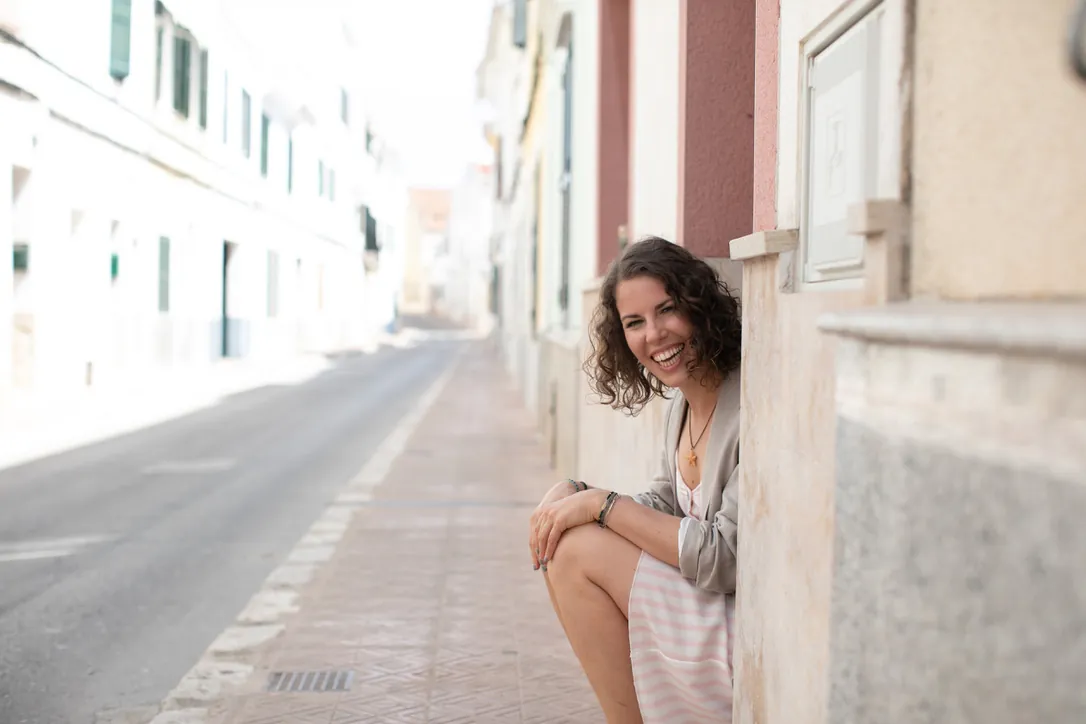 Maria sitting on a doorstep in a quiet whitewashed street