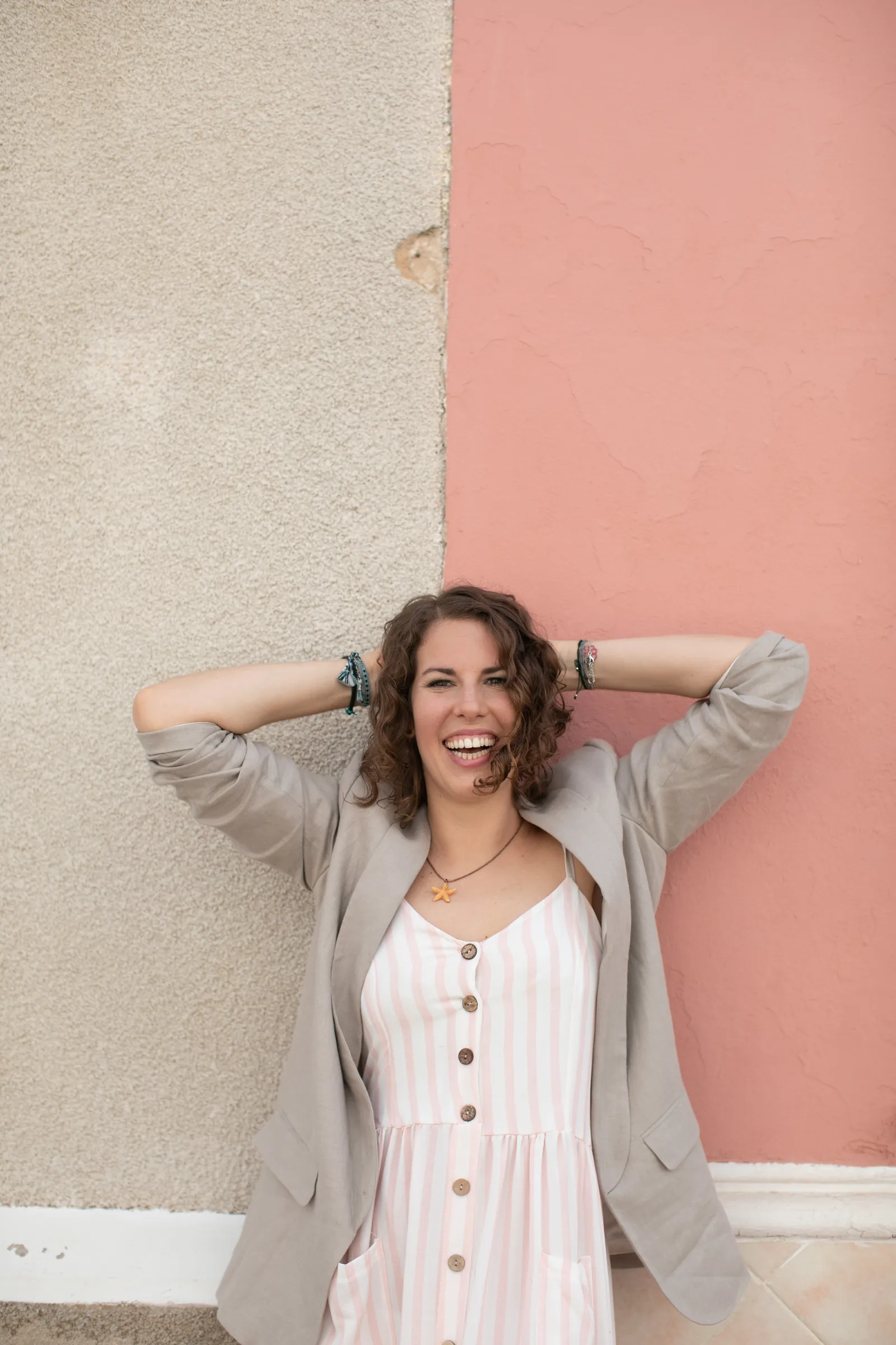 Maria relaxed against a pink wall, hands behind her head